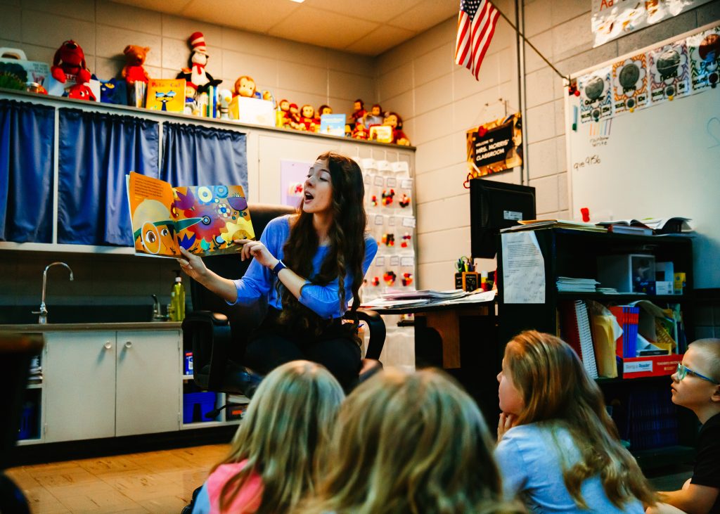 A teacher holding up a book to students